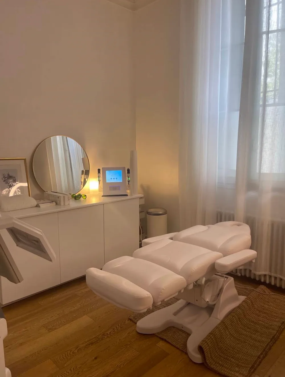 La salle de soin du centre Nihel’s Skintech à Bordeaux : fauteuil de soin blanc, miroir rond, parquet et lumière du jour