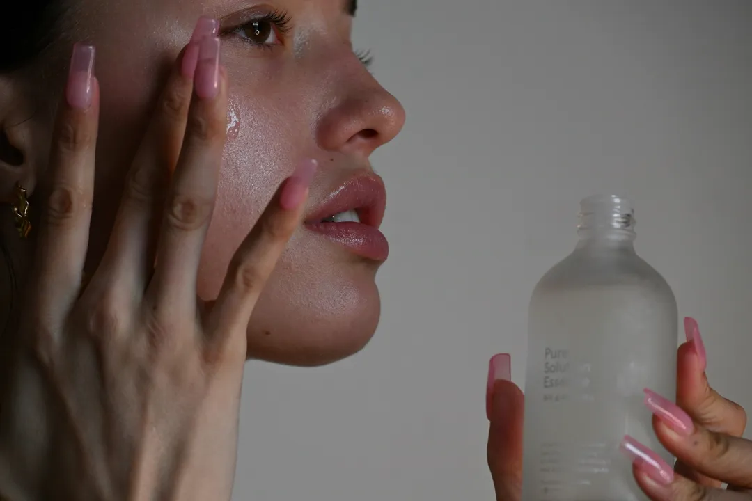 Mains sur le visage, flacon de soin